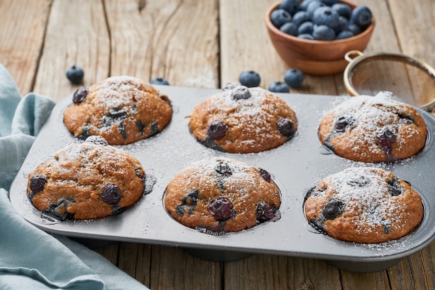 Muffin de blueberry na bandeja, vista lateral. Cupcakes com bagas em assadeira no antigo guardanapo de linho