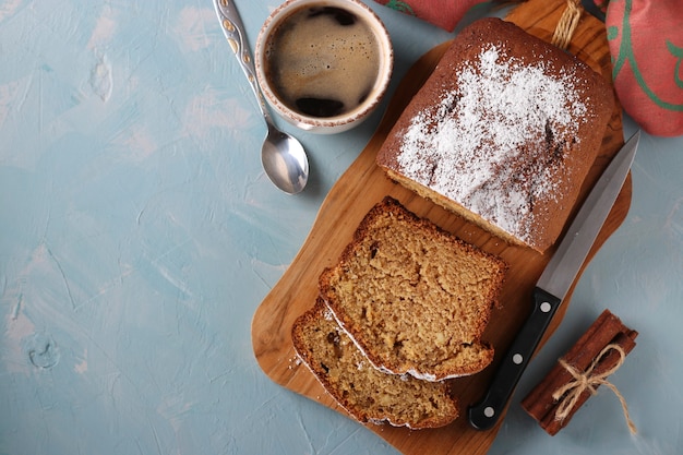 Muffin de café caseiro em uma placa de madeira e uma xícara de café em um fundo azul claro, espaço de cópia, vista superior