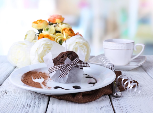Muffin de chocolate com calda de chocolate no prato na mesa de madeira sobre fundo brilhante
