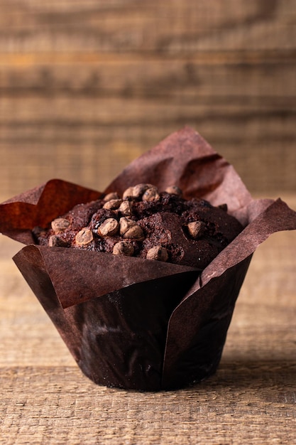 Muffin de chocolate escuro com chips de chocolate e gotas em uma mesa de madeira