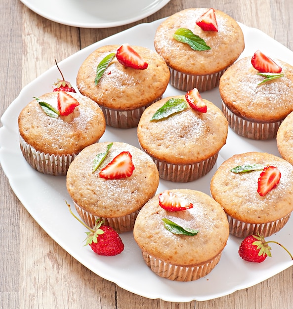 Muffin de morango em um prato branco com um morango fresco