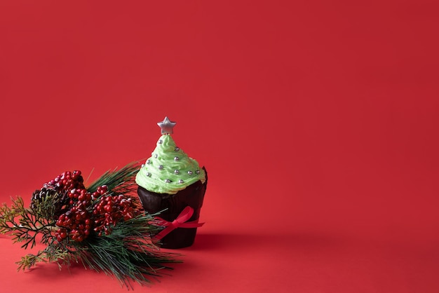 Muffin festivo, cupcake de Navidad con top crema verde y estrella sobre fondo rojo, copie el espacio.