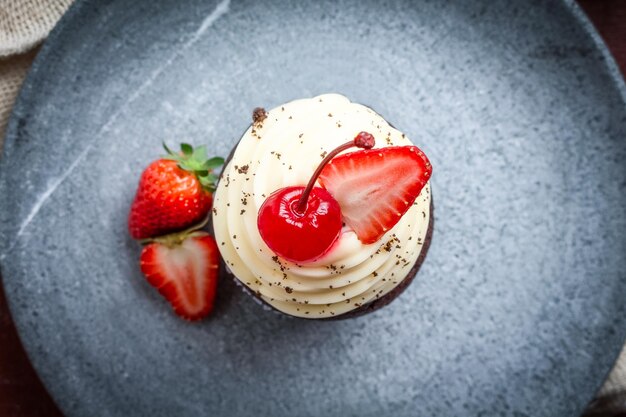 Muffin con fresas y cerezas en un plato de piedra gris.