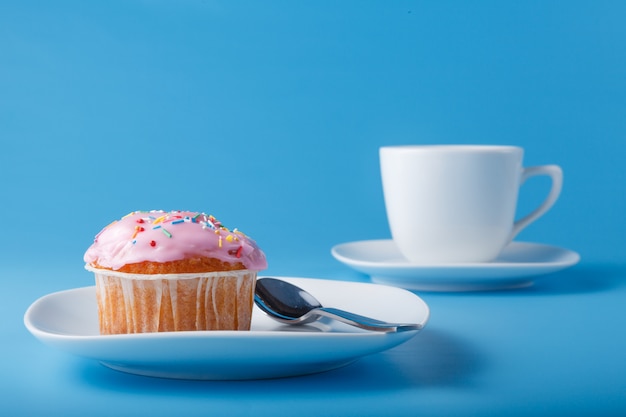 Muffin con glaseado en un plato y una taza