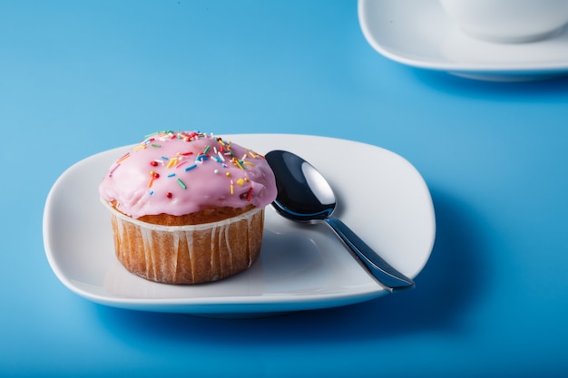 Muffin con glaseado en un plato y una taza