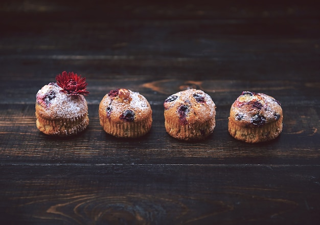 Muffin mit Johannisbeeren auf dunklem Hintergrund neben den Beeren an den Zweigen. im rustikalen Stil. dunkler Stil