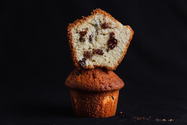 Muffin mit Rosinen und einem halbierten Muffin auf schwarzem Hintergrund
