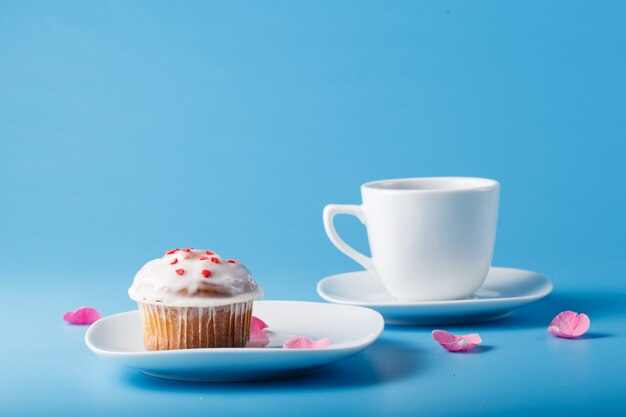 Muffin mit Zuckerguss auf einem Teller und einem Becher