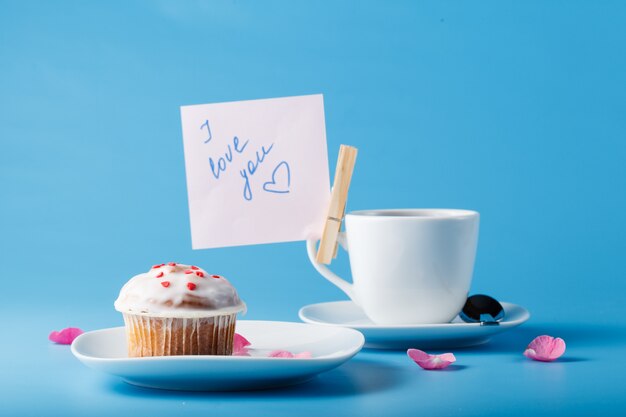 Muffin mit Zuckerguss auf einem Teller und einem Becher