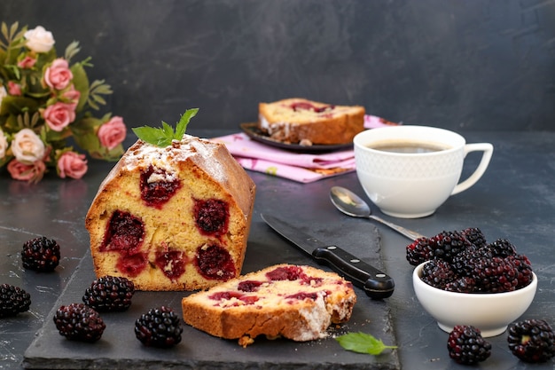 Un muffin de moras se encuentra en una tabla de pizarra en un oscuro