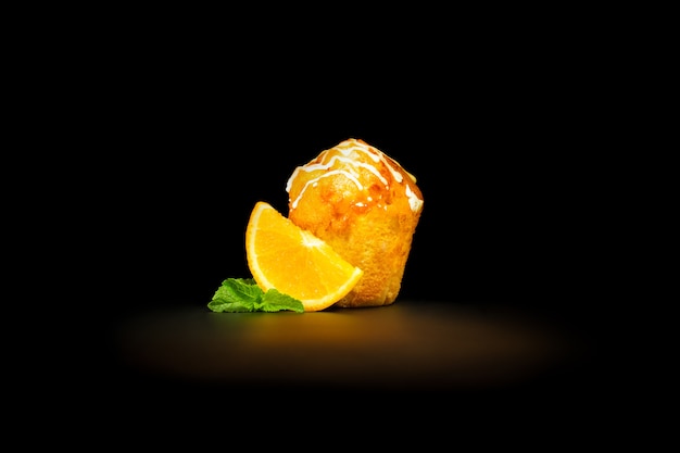 Muffin de naranja con una rodaja de hojas de naranja y menta, bañadas con glaseado