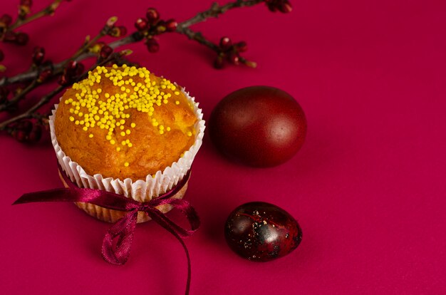 Muffin de Pascua decorado con cinta y rociado, huevos de colores, tarjeta de felicitación.