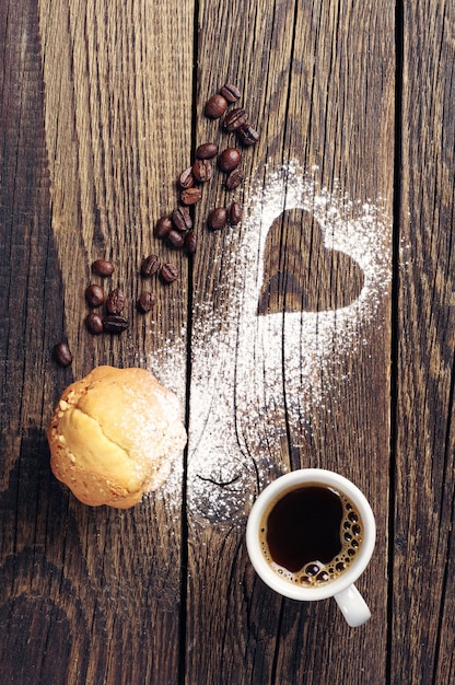 Foto muffin und tasse kaffee auf vintage-holz-hintergrund mit herz