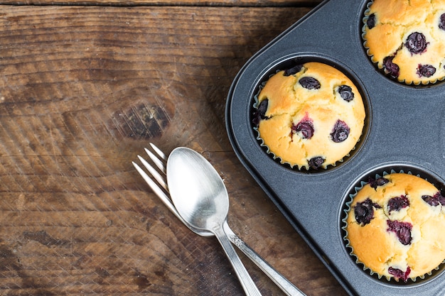 muffins de arándanos con el azúcar en polvo y bayas frescas