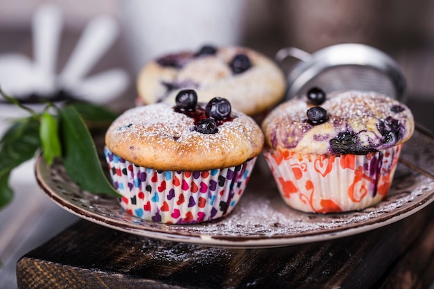 Muffins de arándanos caseros con azúcar en polvo sobre fondo de madera