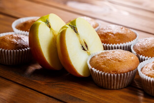 Muffins caseiros embrulhados em papel com uma maçã em uma placa de madeira