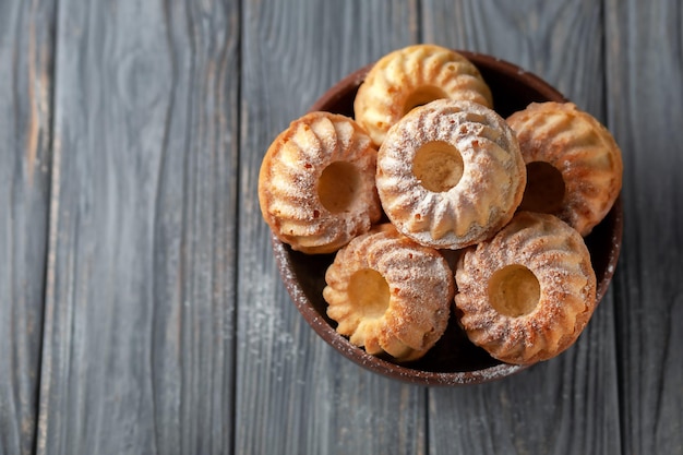 Muffins caseiros recém-assados em tigela de cerâmica com fundo de madeira