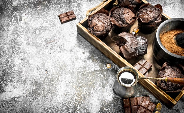 Muffins de chocolate con café caliente en la mesa rústica.