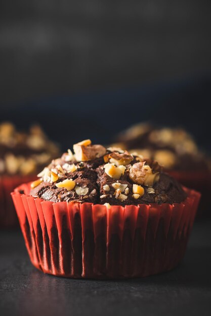 Muffins de chocolate caseros o cupcakes espolvoreados de nueces sobre fondo oscuro