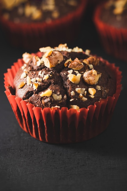 Muffins de chocolate caseros o cupcakes espolvoreados de nueces sobre fondo oscuro