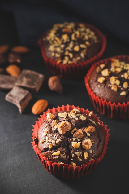 Muffins de chocolate caseros o cupcakes espolvoreados de nueces sobre fondo oscuro