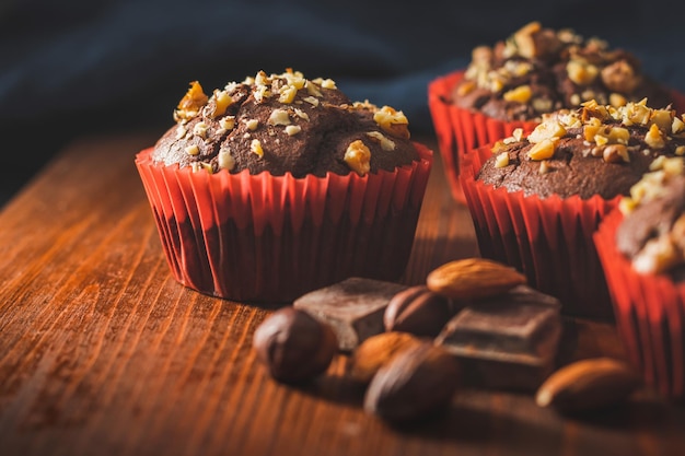 Muffins de chocolate caseros o cupcakes espolvoreados de nueces sobre una tabla de madera