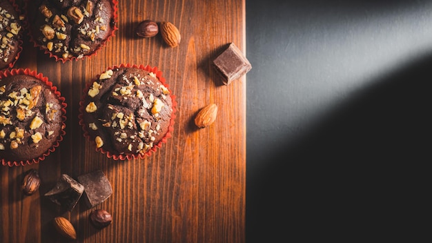 Muffins de chocolate caseros o cupcakes espolvoreados con nueces en una vista superior de tablero de madera