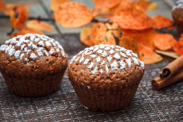 Muffins de chocolate con relleno de manzana sobre un fondo de hojas de otoño y canela