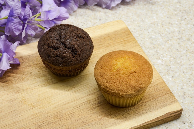 Muffins de chocolate y vainilla con fondo floral y de madera