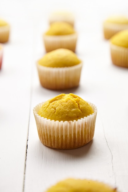 Muffins en el cuadro blanco, primer plano, enfoque selectivo. Cupcakes de calabaza o naranja cocidos sobre fondo de madera. Panadería casera