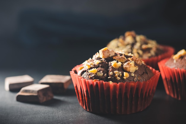 Muffins de chocolate caseiros ou cupcakes polvilhados de nozes em fundo escuro