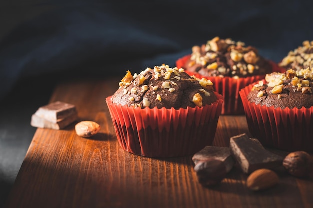 Muffins de chocolate caseiros ou cupcakes polvilhados de nozes em uma placa de madeira