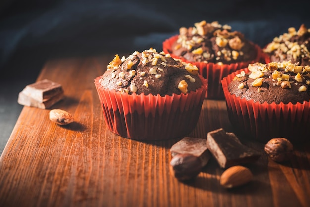 Muffins de chocolate caseiros ou cupcakes polvilhados de nozes em uma placa de madeira