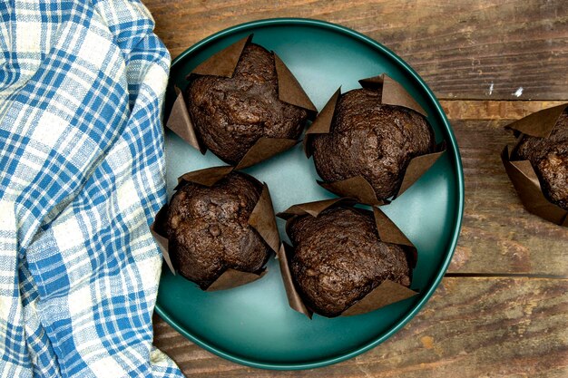 muffins de chocolate caseiros ou madeleine em prato verde em mesa de madeira