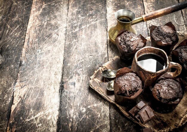 Muffins de chocolate com café quente. Em uma mesa de madeira.