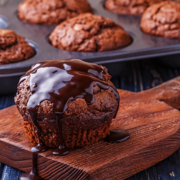Muffins de chocolate com calda de chocolate em fundo escuro, foco seletivo.