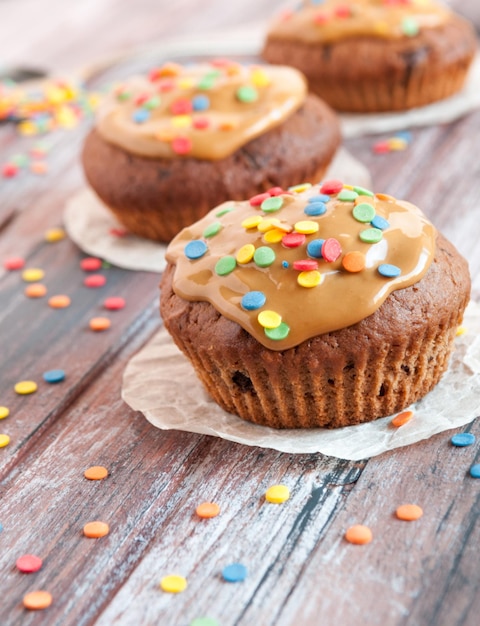 Muffins de chocolate Com caramelo e toque multicolorido Geometria Um fundo de madeira é desfocado