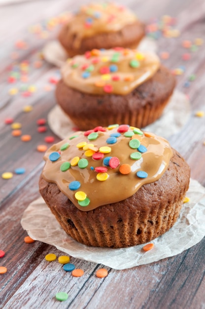 Muffins de chocolate Com caramelo e toque multicolorido Geometria Um fundo de madeira é desfocado