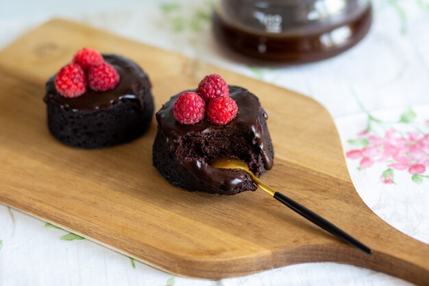 Muffins de chocolate com cobertura mordida em um pedaço de fondant de chocolate em uma colher de lava caseira