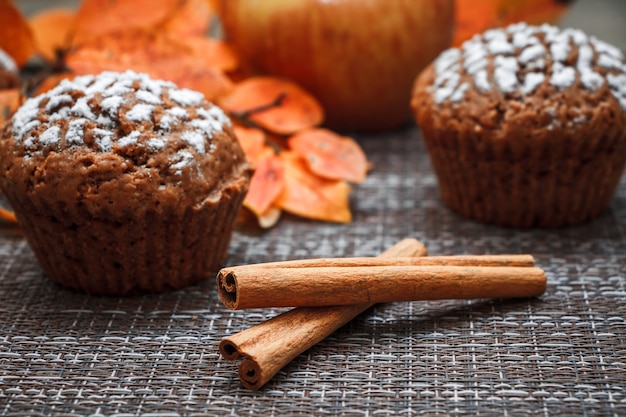Foto muffins de chocolate com recheio de maçã em um fundo de folhas de outono e canela