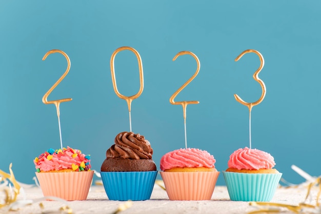 Muffins de férias com creme de manteiga rosa e números de 2023 em fundo azul Feliz Ano Novo