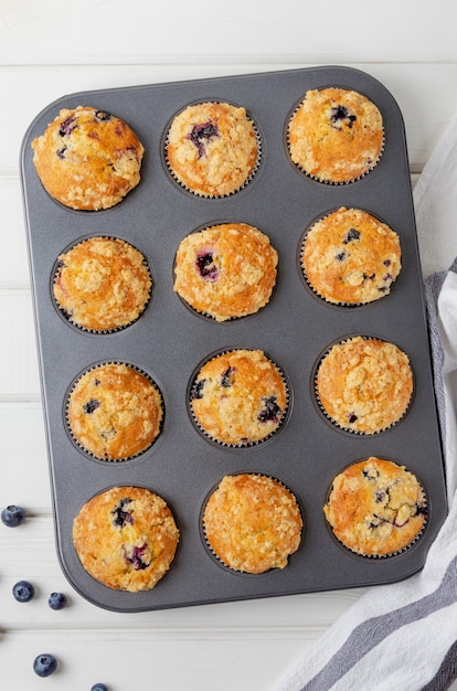 Muffins de limão prontos com mirtilos e shtreisel em forma de cozimento em um fundo branco de madeira