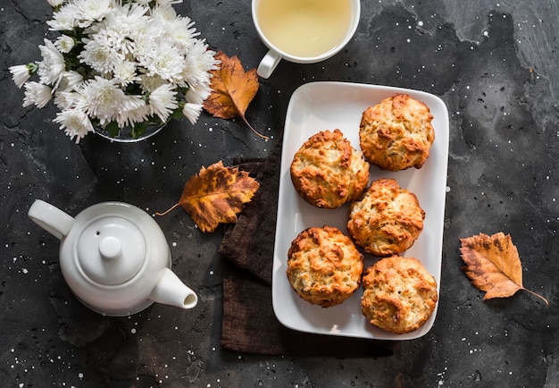 Muffins de maçãs de canela caramelizadas, chá verde, buquê de crisântemos em um fundo escuro