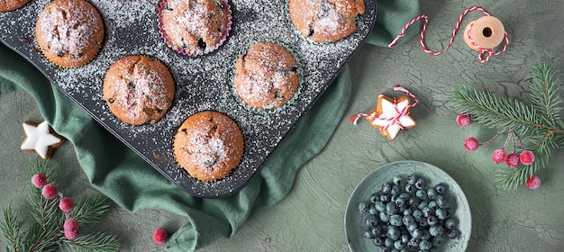 Muffins de mirtilo com cobertura de açúcar em uma assadeira. Imagem panorâmica de vista superior com decoração de Natal