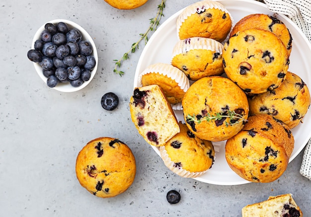 Muffins de mirtilo de banana vegan saudável em uma tigela de cerâmica branca com frutas vermelhas, tomilho e hortelã