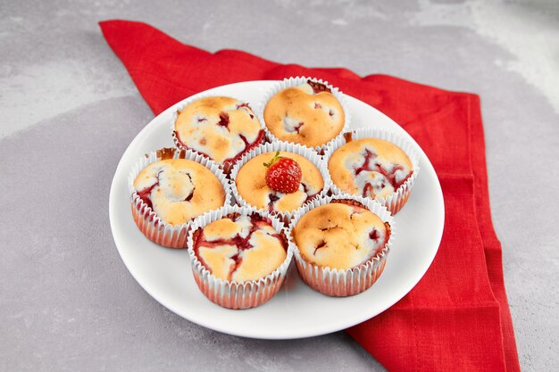 Muffins de morango caseiros em prato branco sobre guardanapo de linho vermelho