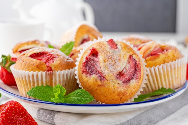 Muffins de morango caseiros ou cupcakes em um prato sobre fundo branco de madeira Foco seletivo