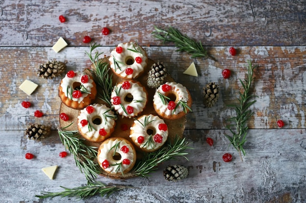 Muffins de Natal com alecrim, glacê branco e frutas vermelhas. Bolos de férias elegantes. Composição de Natal.