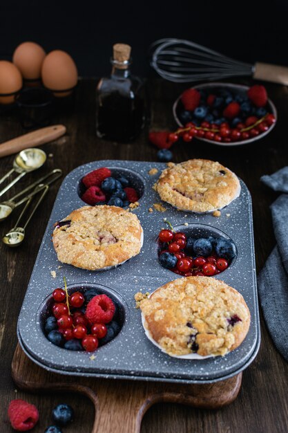 Muffins de streusel com mirtilo, framboesa e groselha na mesa de madeira rústica