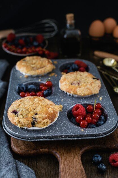 Muffins de Streusel com mirtilo, framboesa e groselha na mesa de madeira rústica